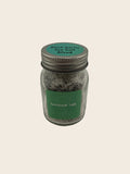 Jar of black garlic salt blend with a green label on a gray background