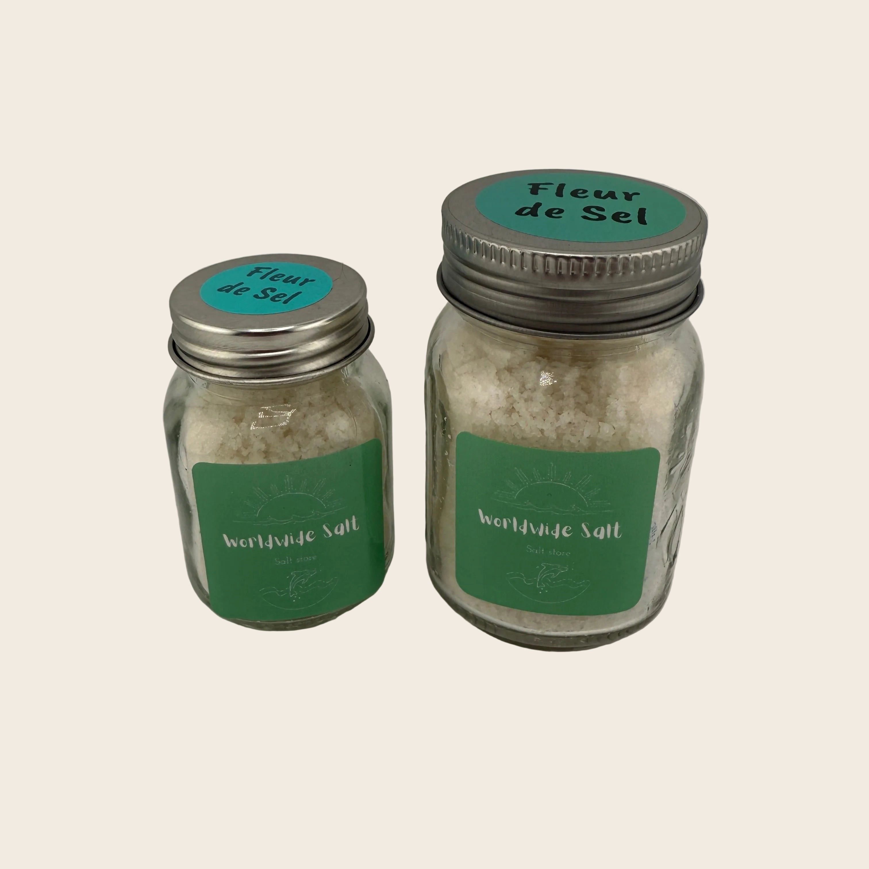 Two jars of 'Fleur de Sel' salt with green labels on a gray background