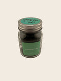 Jar of Himalayan black salt with green label on a beige background