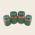 Four jars of pink Himalayan salt with green labels on a gray background