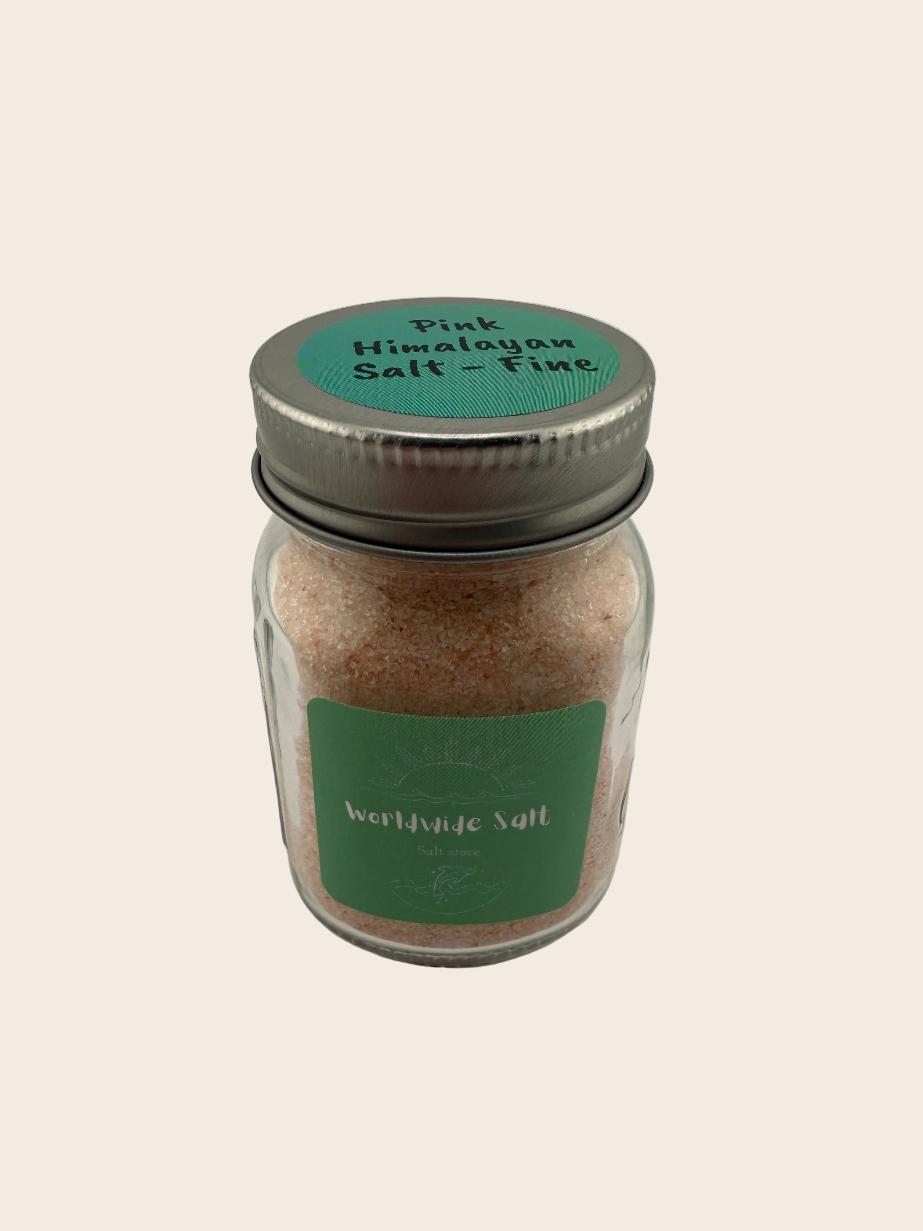 Jar of pink Himalayan salt with a green label on a light gray background
